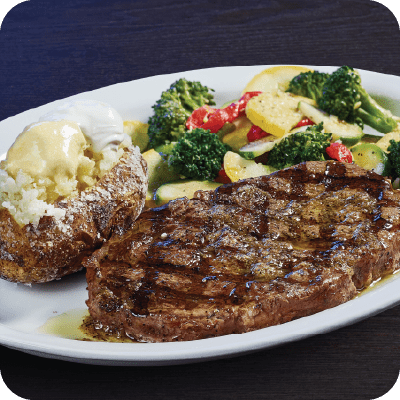 ribeye steak with a baked potato and veggies