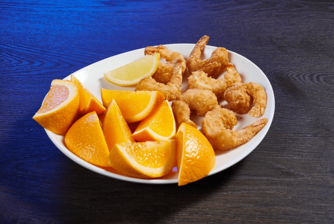 fried shrimp platter of seven on a plate with orange slices