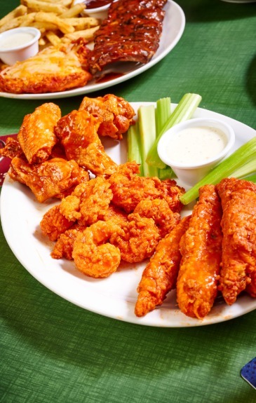 a plate of zingers, wings and shrimp tossed in buffalo sauce