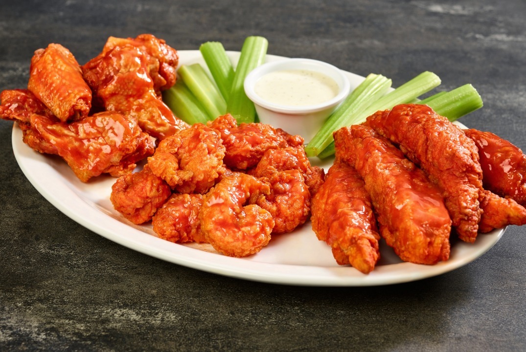 a plate of zingers, wings and shrimp tossed in buffalo sauce