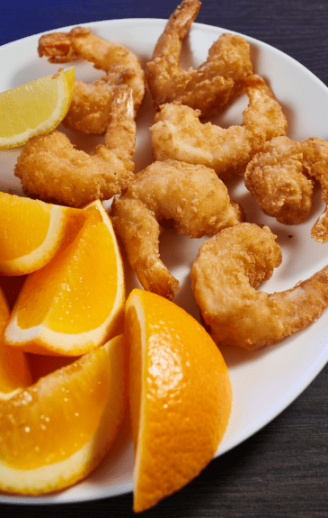 fried shrimp platter of seven on a plate with orange slices